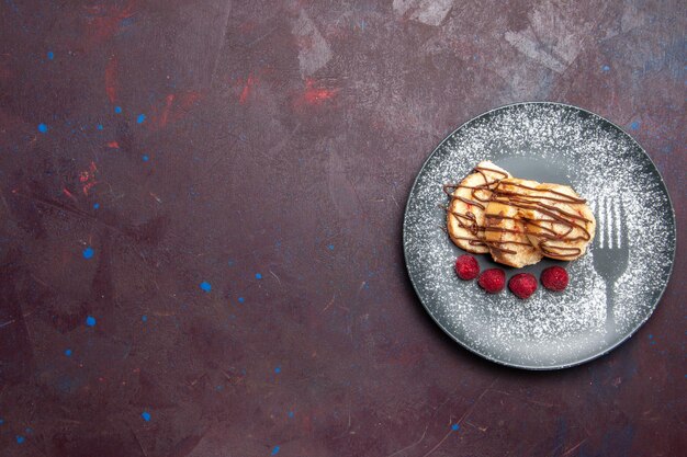 Vue de dessus de délicieux petits pains sucrés en tranches de gâteau pour le thé à l'intérieur de la plaque sur une table noire