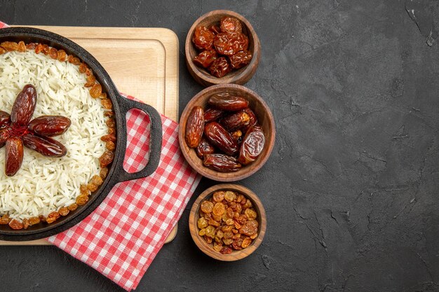 Vue de dessus délicieux plat de riz cuit plov avec différents raisins secs sur fond sombre plat de riz aux raisins secs alimentaire dîner huile