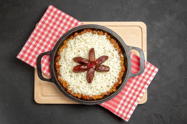 Vue de dessus délicieux plat de riz cuit plov avec des raisins secs sur fond sombre plat de riz aux raisins secs alimentaire dîner huile