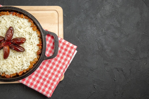 Vue de dessus délicieux plat de riz cuit plov avec des raisins secs sur fond sombre plat de riz aux raisins secs alimentaire dîner huile