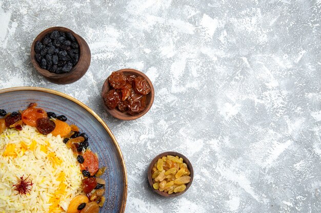 Vue de dessus délicieux plat de riz cuit shakh plov avec des raisins secs à l'intérieur de la plaque sur blanc