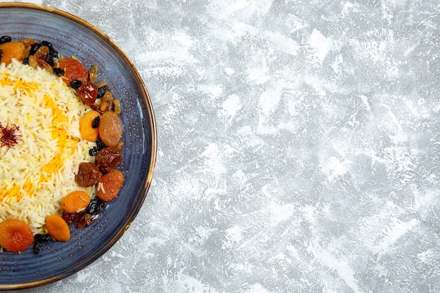 Vue de dessus délicieux plat de riz cuit shakh plov avec des raisins secs à l'intérieur de la plaque sur un bureau blanc