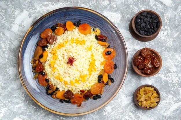 Vue de dessus délicieux plat de riz cuit shakh plov avec des raisins secs à l'intérieur de la plaque sur le sol blanc