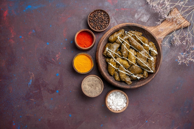 Vue de dessus délicieux plat de viande dolma avec différents assaisonnements sur fond sombre nourriture calorie plat dîner viande