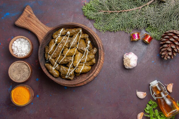 Vue de dessus délicieux plat de viande dolma feuille avec différents assaisonnements sur le fond sombre plat de dîner de viande nourriture calorie couleur