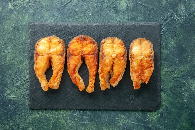 Vue de dessus délicieux poisson frit sur la surface sombre plat salade alimentaire frire viande poivre de mer cuisson repas fruits de mer