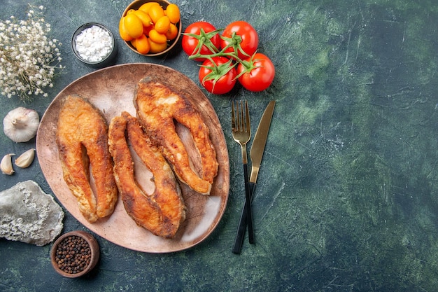 Vue de dessus de délicieux poissons frits sur une assiette brune et des couverts d'épices sur la table des couleurs de mélange avec de l'espace libre
