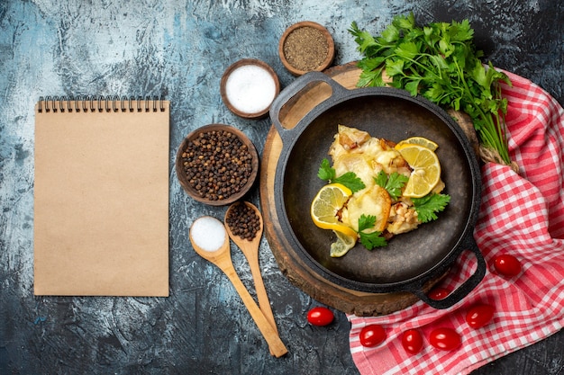 Vue de dessus de délicieux poissons frits au citron et au persil dans une poêle sur une planche de bois