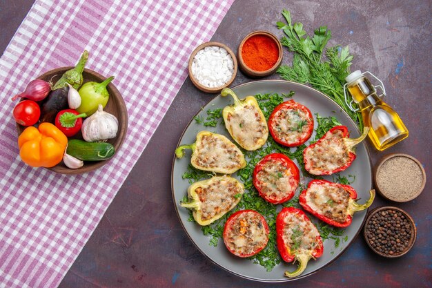 Vue de dessus de délicieux poivrons délicieux repas cuisinés avec de la viande et des légumes verts sur un bureau sombre dîner repas plat poivre nourriture épicée