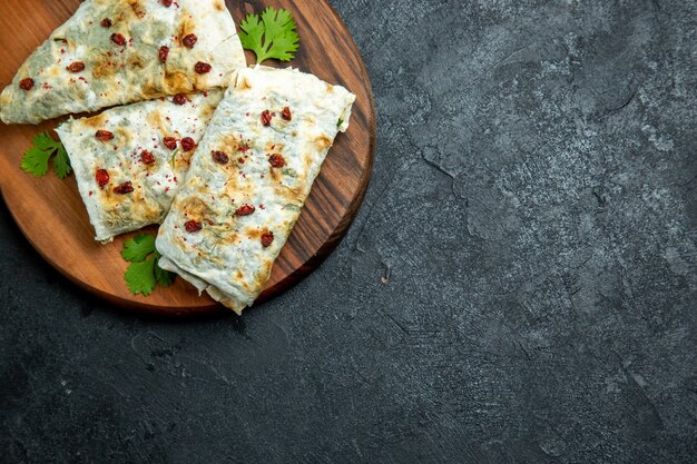 Vue de dessus de délicieux qutabs roulés des tranches de pâte remplies de vert sur l'espace gris