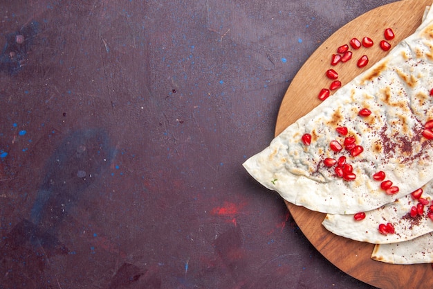 Vue de dessus de délicieux qutabs de viande pitas avec des grenades rouges fraîches sur pita repas de pâte de viande de bureau violet