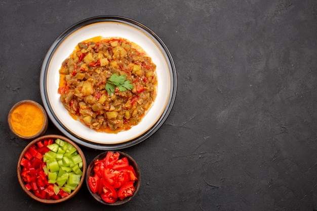 Vue de dessus délicieux repas de légumes plat cuit en tranches à l'intérieur de la plaque sur fond gris repas dîner nourriture sauce soupe légumes