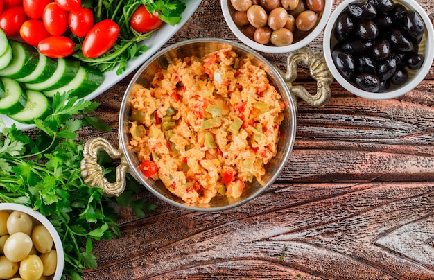 Vue de dessus délicieux repas en pot avec salade, cornichons dans des bols sur une surface en bois