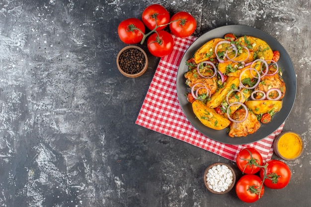 Vue de dessus d'un délicieux repas de poulet avec des pommes de terre et des légumes verts sur des tomates de serviette dénudées rouges pliées avec des tiges d'épices sur une table de couleur foncée