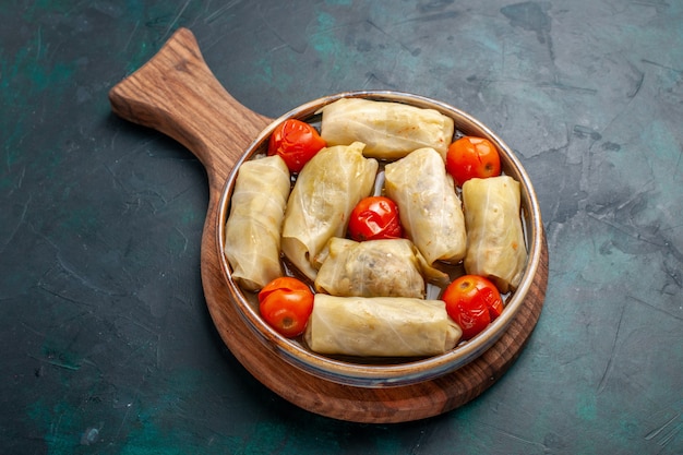 Vue de dessus délicieux repas de viande roulé à l'intérieur du chou avec des tomates sur la surface bleu foncé viande nourriture dîner calories plat de légumes cuisson