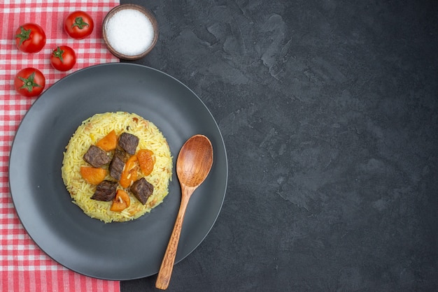 Vue de dessus délicieux riz cuit pilaf avec des tranches de viande sel et tomates sur une surface sombre