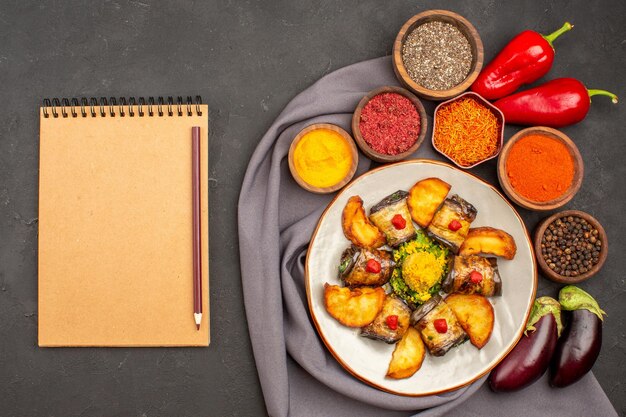 Vue de dessus de délicieux rouleaux d'aubergines plat cuisiné avec des pommes de terre au four et des assaisonnements sur un bureau sombre plat de repas cuisson de pommes de terre