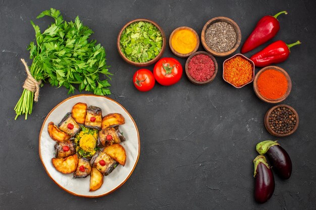 Vue de dessus de délicieux rouleaux d'aubergines avec pommes de terre au four et assaisonnements sur fond noir