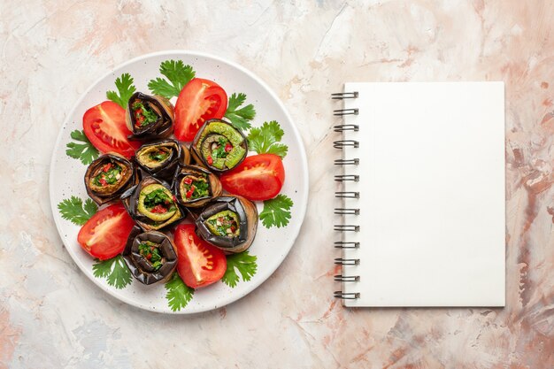 Vue de dessus de délicieux rouleaux d'aubergines avec des verts et des tomates