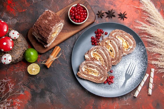 Vue de dessus de délicieux rouleaux de biscuits aux fruits sur un bureau sombre