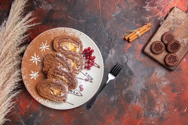 Vue de dessus de délicieux rouleaux de biscuits avec des cookies sur une table sombre