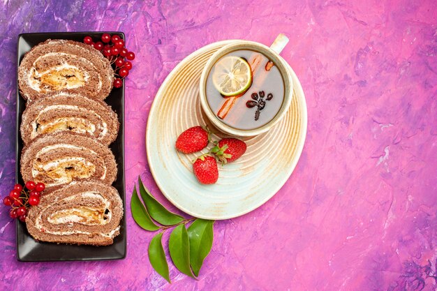 Vue de dessus de délicieux rouleaux de biscuits avec une tasse de thé sur fond rose