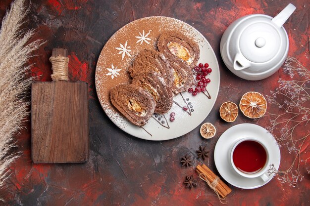 Vue de dessus de délicieux rouleaux de biscuits avec une tasse de thé sur une table sombre