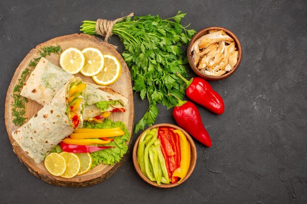 Vue de dessus d'un délicieux sandwich au poulet tranché shaurma avec des verts de citron sur l'obscurité