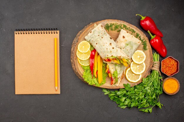 Vue de dessus d'un délicieux sandwich au poulet tranché shaurma avec des verts de citron sur l'obscurité