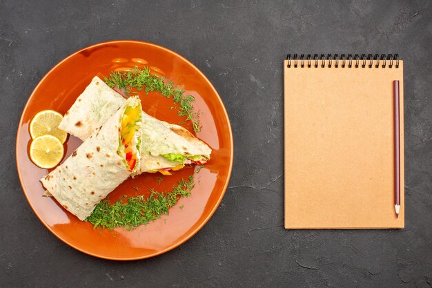 Vue de dessus délicieux sandwich à la salade de shaurma en tranches à l'intérieur de la plaque sur le fond sombre burger repas sandwich pain collation