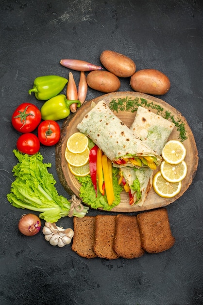 Vue de dessus d'un délicieux sandwich à la viande de shaurma en tranches avec du pain et des légumes sur un tableau noir