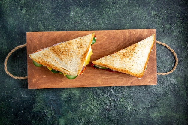 Vue de dessus de délicieux sandwichs au jambon sur une surface sombre de planche de bois
