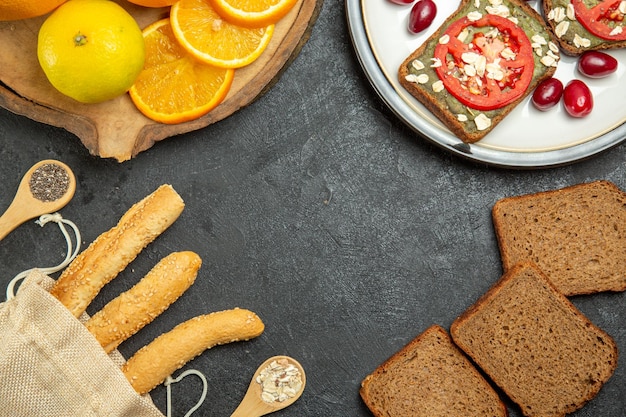 Vue de dessus de délicieux sandwichs à l'avocat avec des oranges sur une surface grise