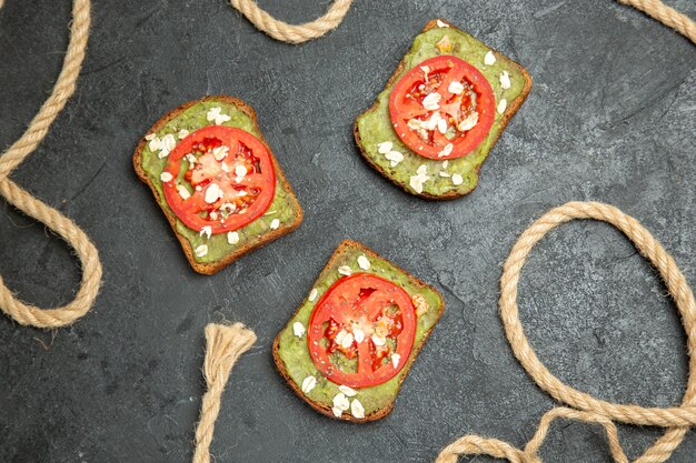 Vue de dessus de délicieux sandwichs avec du wassabi et des tomates rouges sur une surface gris foncé pain burger sandwich repas snack