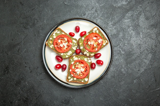 Vue de dessus de délicieux sandwichs utiles avec des pâtes à l'avocat et des tomates à l'intérieur de la plaque sur un fond gris burger sandwich pain pain snack