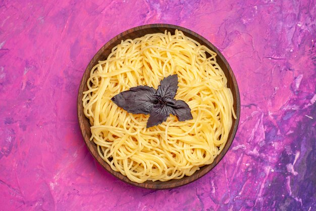 Vue de dessus de délicieux spaghettis cuits à l'intérieur de la plaque sur un plat de repas de pâte de pâte de table rose