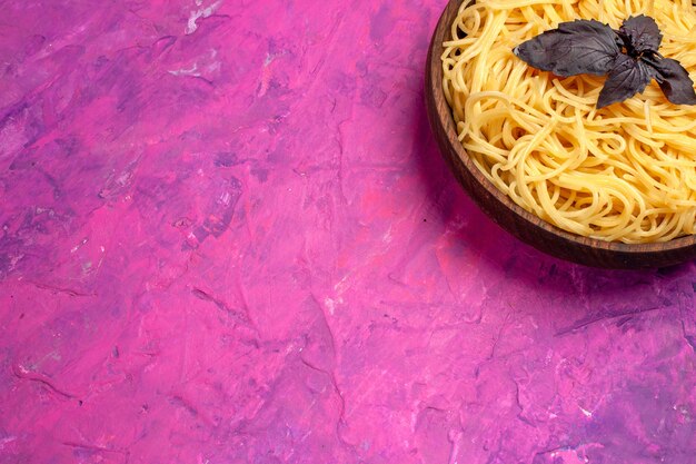 Vue de dessus de délicieux spaghettis cuits à l'intérieur de la plaque sur un repas de pâte de pâtes de table rose