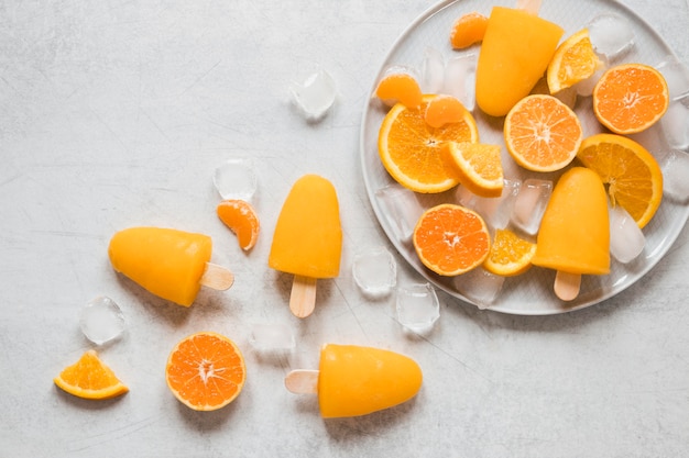 Vue de dessus de délicieux sucettes glacées sur plaque avec glace et orange