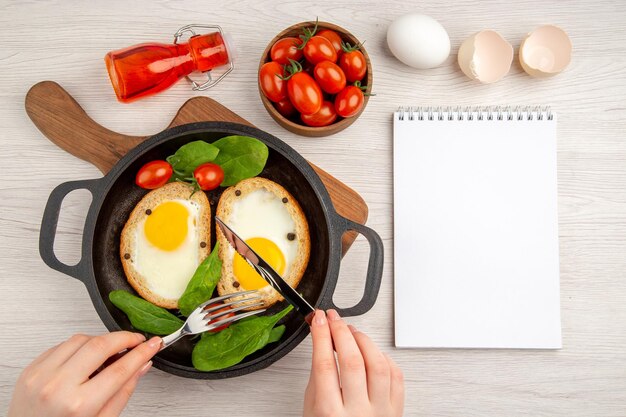 Vue de dessus de délicieux toasts aux œufs se faire manger par une femme sur fond blanc nourriture salade plat pain couleur repas déjeuner petit déjeuner