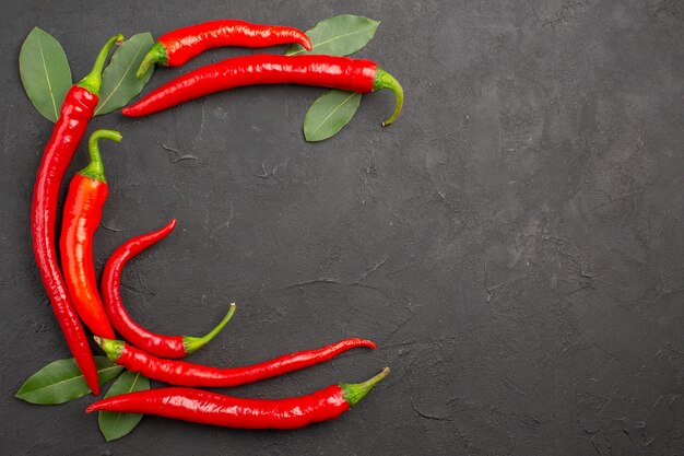 Vue de dessus demi-cercle de piments rouges et de feuilles de laurier sur le côté gauche de la table noire