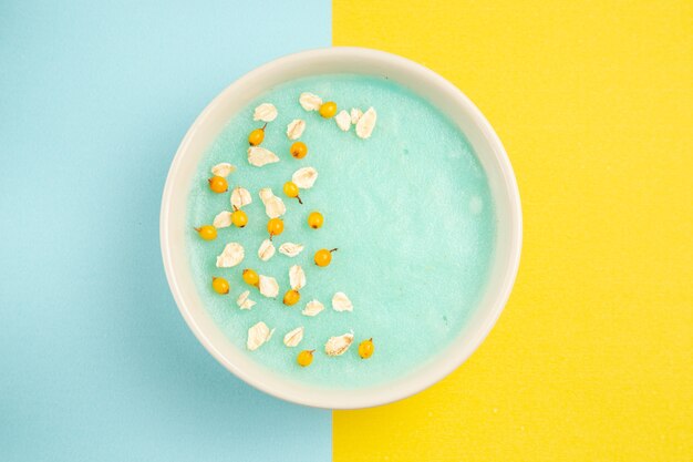 Vue de dessus dessert glacé bleu à l'intérieur de la plaque sur les céréales de couleur lait de table bleu-jaune