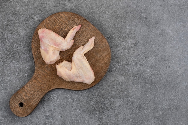 Photo gratuite vue de dessus de deux ailes de poulet crues fraîches sur une planche à découper en bois