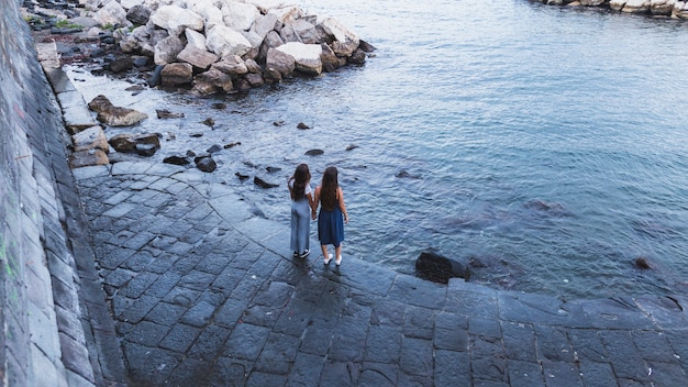 Une vue de dessus de deux jeunes femmes debout près de la côte