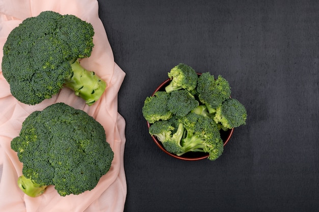 Vue de dessus deux tas de brocoli sur un tissu rose avec du brocoli dans un bol en céramique