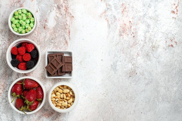 Vue de dessus de différentes baies d'arachides collations et bonbons sur une surface blanche légère