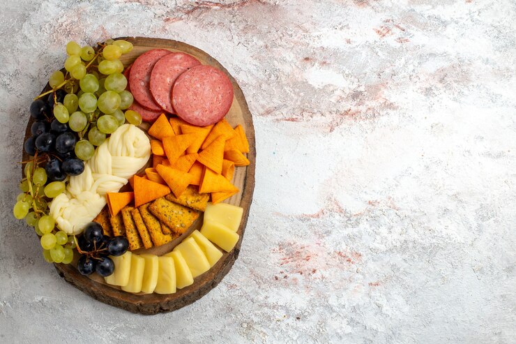 Photo gratuit vue de dessus différentes collations cips saucisses fromage et raisins frais sur espace blanc