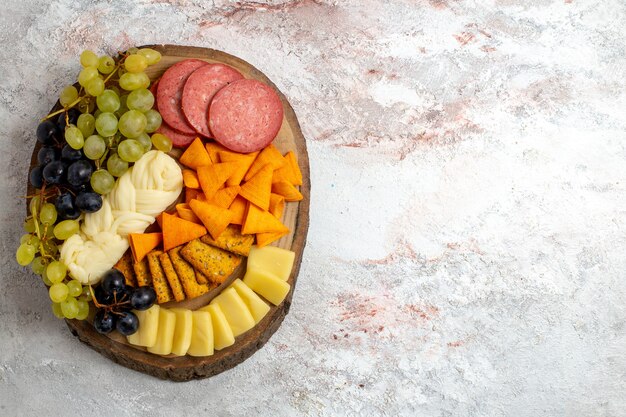 Vue de dessus différentes collations cips saucisses fromage et raisins frais sur espace blanc