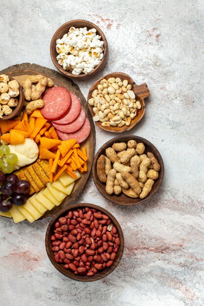 Vue de dessus différentes collations noix cips raisins fromage et saucisses sur la surface blanche noix snack-repas alimentaire fruit