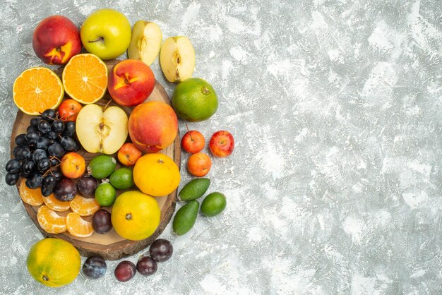 Vue de dessus différentes compositions de fruits tranchés et fruits frais entiers sur fond blanc arbre vitamine fruits mûrs couleur moelleuse