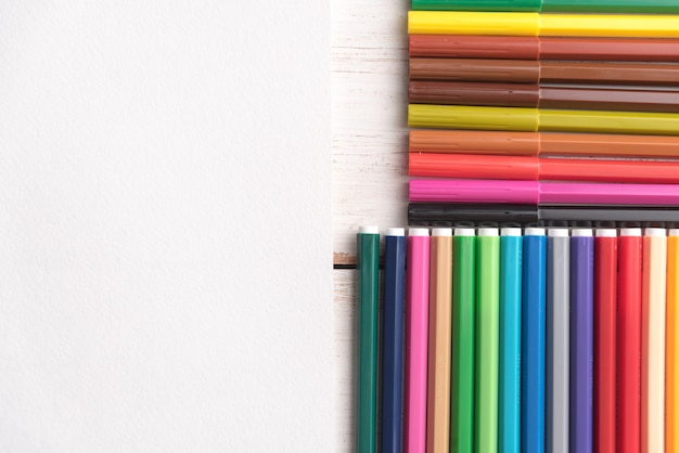 Vue de dessus de différentes couleurs pastel et marqueurs dans des boîtes sur tableau blanc